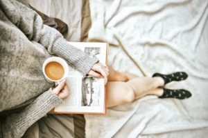 Bücher über Selbstliebe beschrieben durch eine Frau mit einer Kaffeetasse und einem Buch