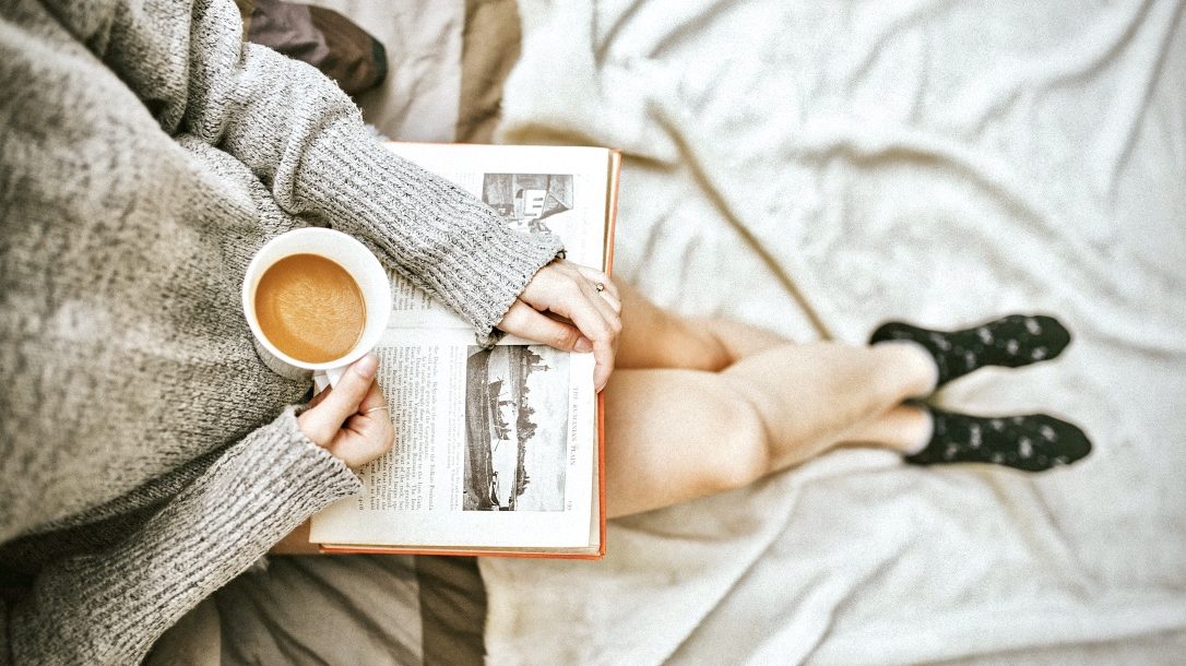 Bücher über Selbstliebe beschrieben durch eine Frau mit einer Kaffeetasse und einem Buch